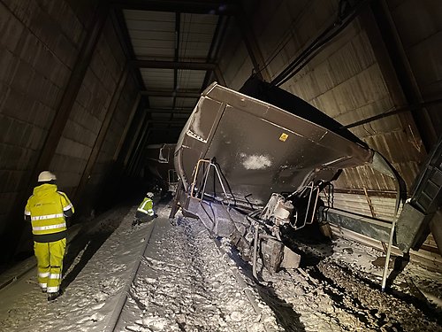 Urspårad tågvagn. Två personer i varselkläder.